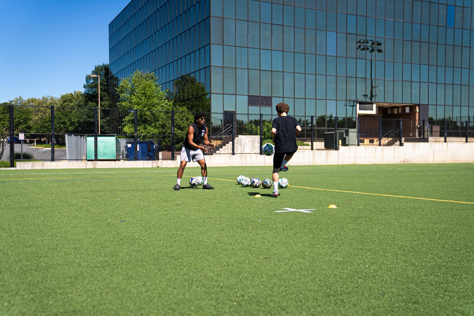Tekne coach feeding balls to a young player during a 1-on-1 first-touch drill on a turf field
